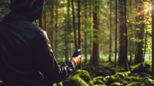 Молодой человек в лесу с телефоном
