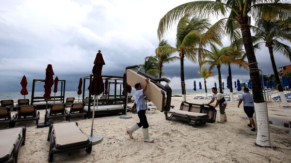 Служащий отеля собирает оборудование в преддверии шторма на побережье Мексики