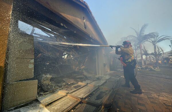 Пожарный тушит дом в Анахайме, Калифорния, США. 9 октября 2017
