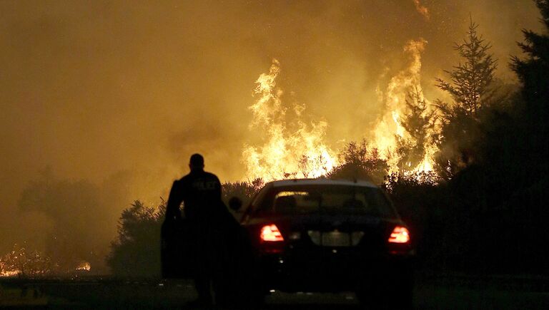 Сотрудник правоохранительных органов блокирует дорогу во время пожара в Санта-Розе, Калифорния, США. 9 октября 2017