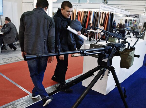 Мужчина осматривает пулемет на выставке Оружие и безопасность в Киеве