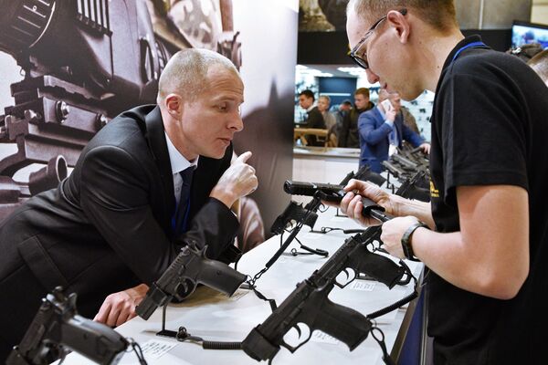 Мужчина осматривает пистолет на выставке Оружие и безопасность в Киеве