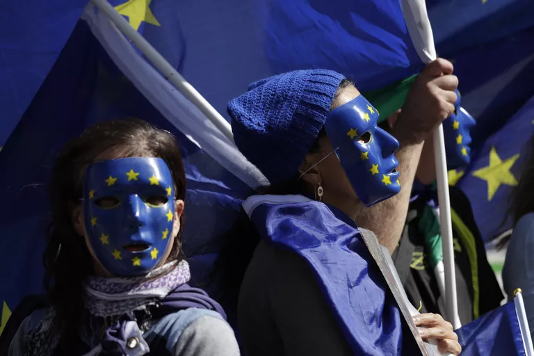 Участники акции протеста против Brexit в масках, стилизованных под флаг Евросоюза, в Лондоне Участники акции протеста против Brexit в масках, стилизованных под флаг Евросоюза, в Лондоне
