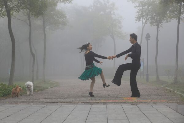 Пара танцует в туманный день в парке Хуайань, Китай