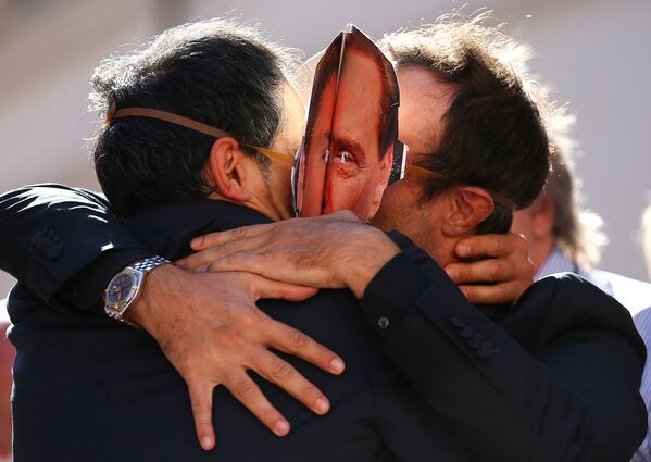 Сторонники итальянской партии Движение пяти звёзд в масках Сильвио Берлускони и Маттео Ренци обнимают друг друга в Риме