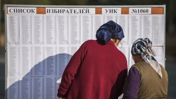 Женщины ищут свои фамилии в списке избирателей на избирательном участке в Бишкеке, чтобы проголосовать на выборах президента Киргизии. 15 октября 2017