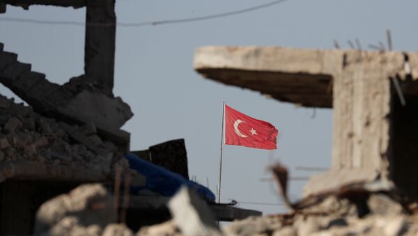Турецкий флаг развивается на границе Турции и Сирии среди зданий, разрушенных в результате борьбы с ИГ*. 11 октября 2017
