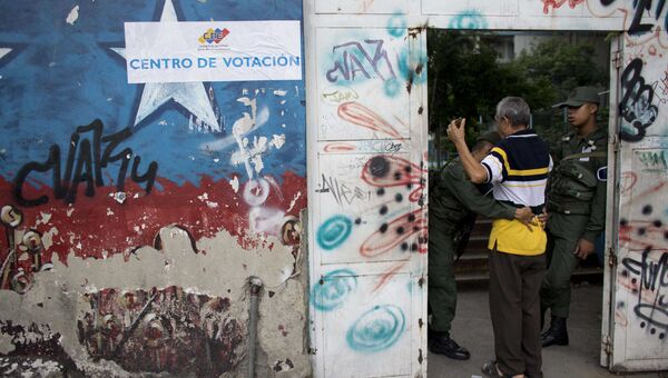 Досмотр жителя Каракаса перед входом на избирательный участок