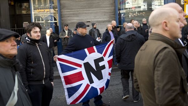 Активист с флагом правой организации Национальный фронт на демонстрации в Англии