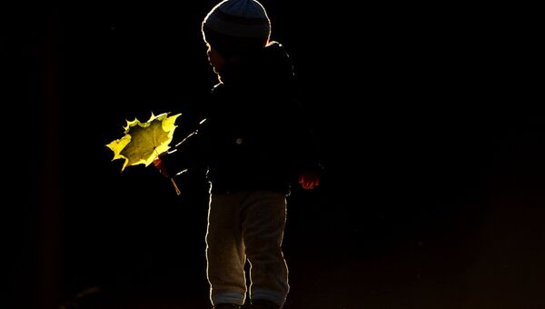 Ребенок играет с осенними листьями