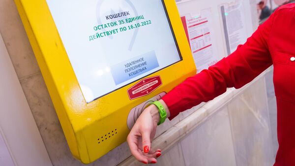 Пассажир московского метро проверяет счет электронного кошелька транспортной карты Тройка с помощью силиконового браслета
