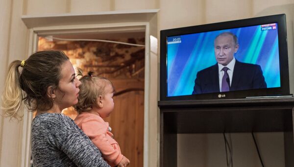 Жительница Омска смотрит трансляцию выступления президента РФ Владимира Путина на итоговой сессии международного дискуссионного клуба Валдай. 19 октября 2017