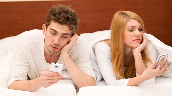 Молодая пара в кровати со смартфонами. Архивное фото