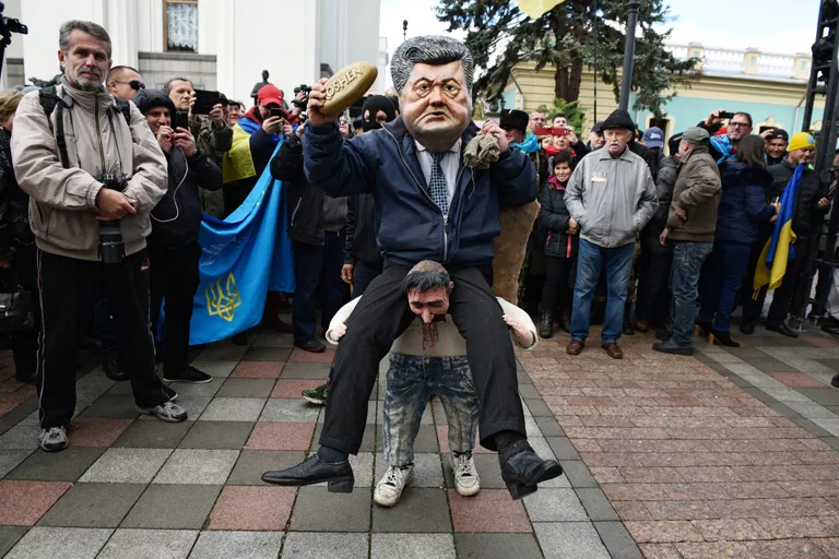 Ряженый в костюме президента Украины Петра Порошенко, который сидит на плечах у украинского казака, во время вече у здания Верховной рады в Киеве Ряженый в костюме президента Украины Петра Порошенко, который сидит на плечах у украинского казака, во время вече у здания Верховной рады в Киеве