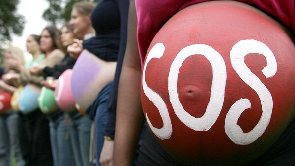 Беременная женщина с надписью SOS на животе на митинге в Лондоне