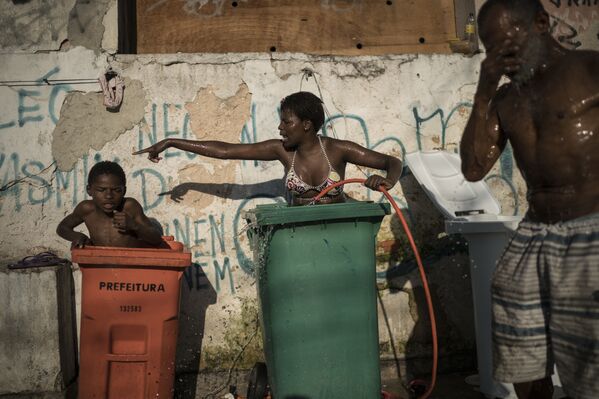 Женщина и ребенок моются в контейнерах для мусора в трущобах Мангейра Рио-де-Жанейро, Бразилия