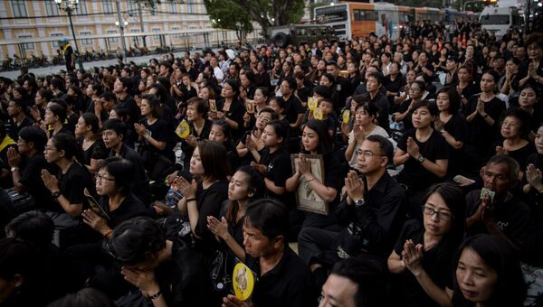 Скорбящие молятся за покойного тайского короля Пхумипона Адульядета во время шествия, передающего реликвии и его прах из Большого дворца в местный храм в Бангкоке. 29 октября 2017