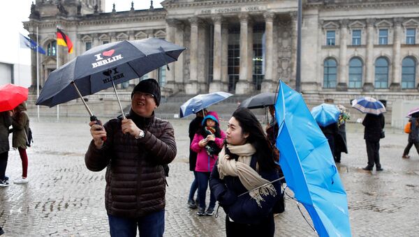 Люди с зонтиками стоят перед Рейхстаг в Берлине, Германия. 29 октября 2017 года