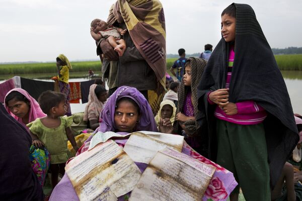 Беженка рохинджа просушивает документы в лагере беженцев в Палонге Хали, Бангладеш