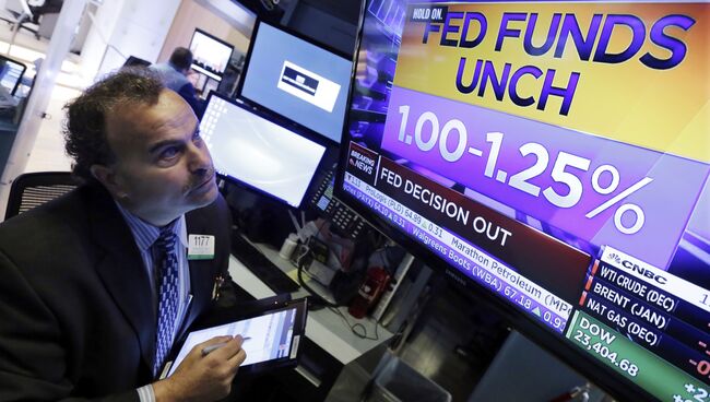 Трейдер смотрит на табло, на котором отображается решение ФРС относительно изменения процентной ставки на Нью-Йоркской фондовой бирже. 1 ноября 2017