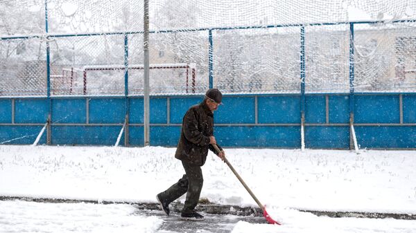 Мужчина убирает снег во дворе жилого дома. Архивное фото
