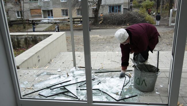 Женщина убирает осколки стекла у здания училища №58 в Донецке, поврежденного в результате ночного обстрела. 6 ноября 2017