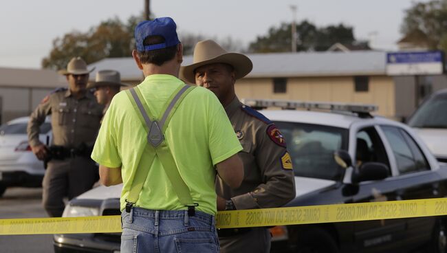 Мужчина разговаривает с сотрудником правоохранительных органов США на месте стрельбы у церкви в Сазерленд-Спрингс в Техасе, США. 5 ноября 2017