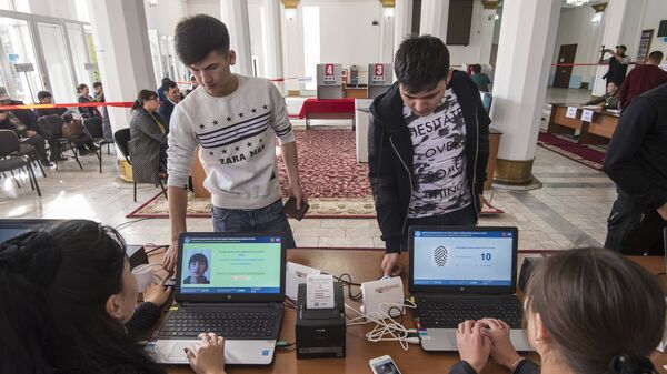 Избиратели проходят процедуру подтверждения личности с помощью сканирования отпечатка пальца на избирательном участке в Бишкеке, перед тем как проголосовать на выборах президента Киргизии