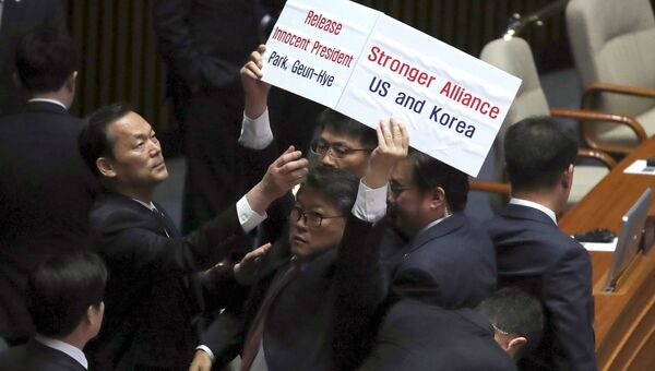 Протестующего выводят из зала южнокорейского парламента перед речью президента США Дональда Трампа. 8 ноября 2017