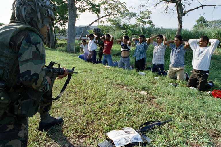 Американский солдат охраняет группу задержанных панамцев. 27 декабря 1989