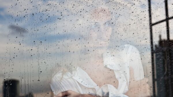 Девушка у окна во время дождя. Архивное фото