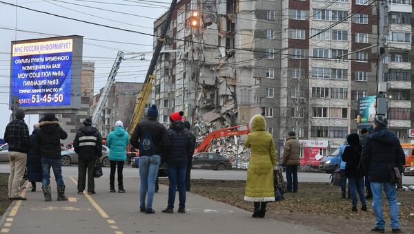 Прохожие наблюдают за ходом работ служб МЧС РФ по расчистке завалов частично обрушившегося жилого панельного дома на Удмуртской улице в Ижевске. 10 ноября 2017