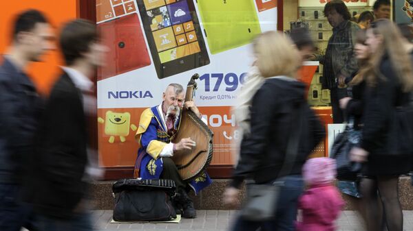Мужчина в национальном украинском костюме играет на домре на улице Киева