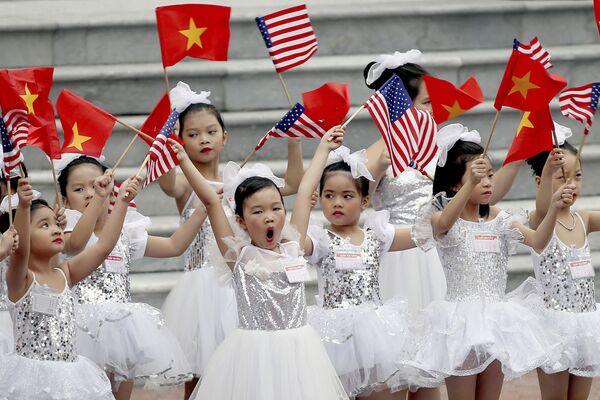 Дети машут флажками перед церемонией приветствия президента США Дональда Трампа в Президентском дворце в Ханое, Вьетнам