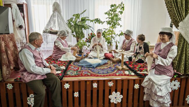 Театрализованное представление в клубе села Татарский Саракташ. Импровизированный дастархан, вокруг которого на курпачах сидят вязальщицы и каждая занята своим делом