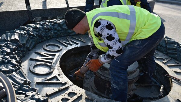 Работник Киевгаз очищают вновь залитый цементом мемориал Вечный огонь в парке Славы в Киеве. 20 ноября 2017