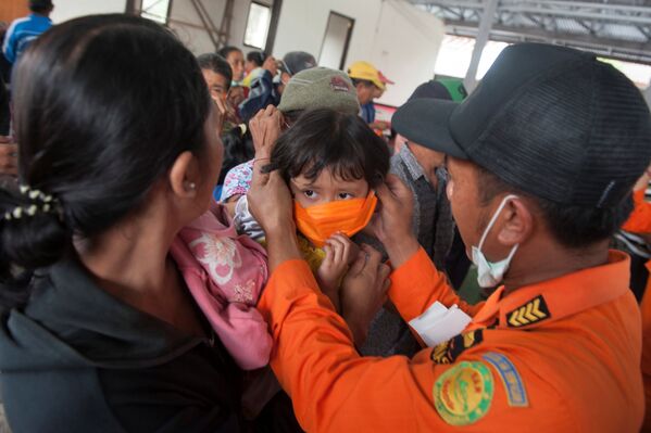Сотрудник BNPB одевает маску ребенку