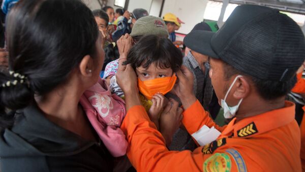 Сотрудник BNPB одевает маску ребенку