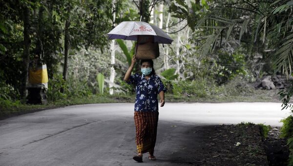 Местная жительница носит маску после извержения вулкана Агунг на острове Бали в Индонезии