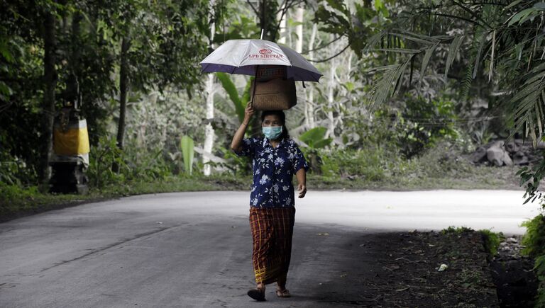 Местная жительница носит маску после извержения вулкана Агунг на острове Бали в Индонезии