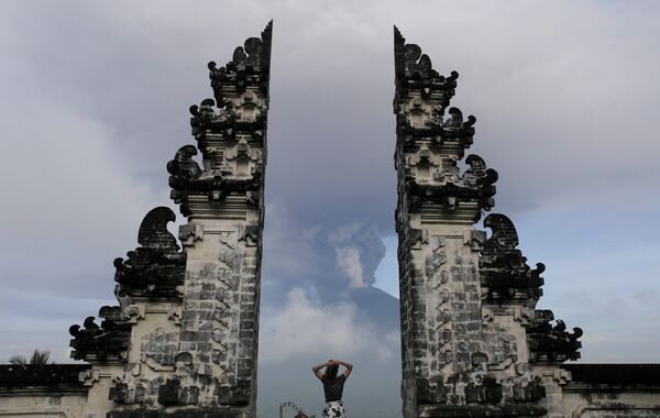 Турист наблюдает за извержением вулкана Агунг на острове Бали в Индонезии