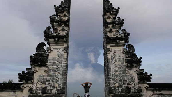 Турист наблюдает за извержением вулкана Агунг на острове Бали в Индонезии