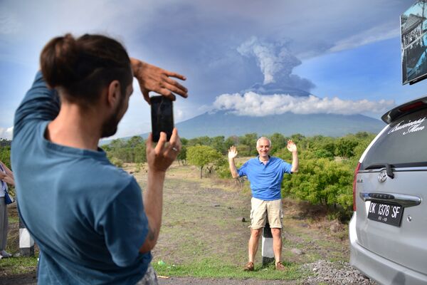 Туристы фотографируются на фоне извержения вулкана Агунг на острове Бали в Индонезии