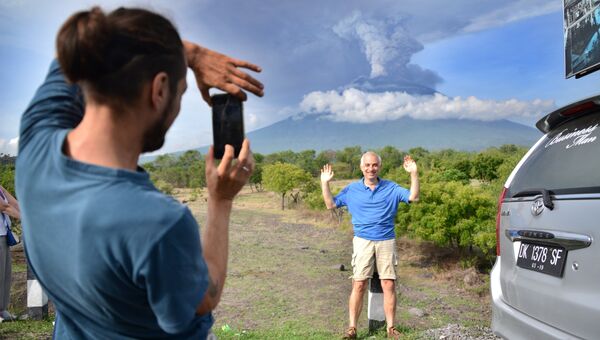 Туристы фотографируются на фоне извержения вулкана Агунг на острове Бали в Индонезии