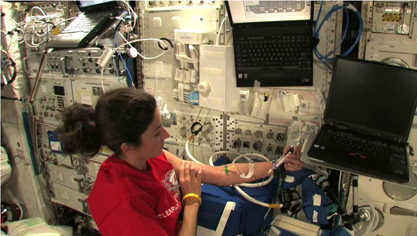 Астронавт Николь Стотт забирает образец крови на борту МКС
