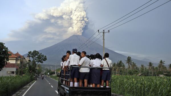 Местные жители по дороге в школу на острове Бали наблюдают за извержением вулкана Агунг, Индонезия. 28 ноября 2017