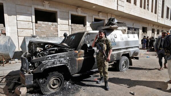 Боевик у сгоревшего бронированного автомобиля недалеко от резиденции президента Йемена Али Абдаллы Салеха в Сане