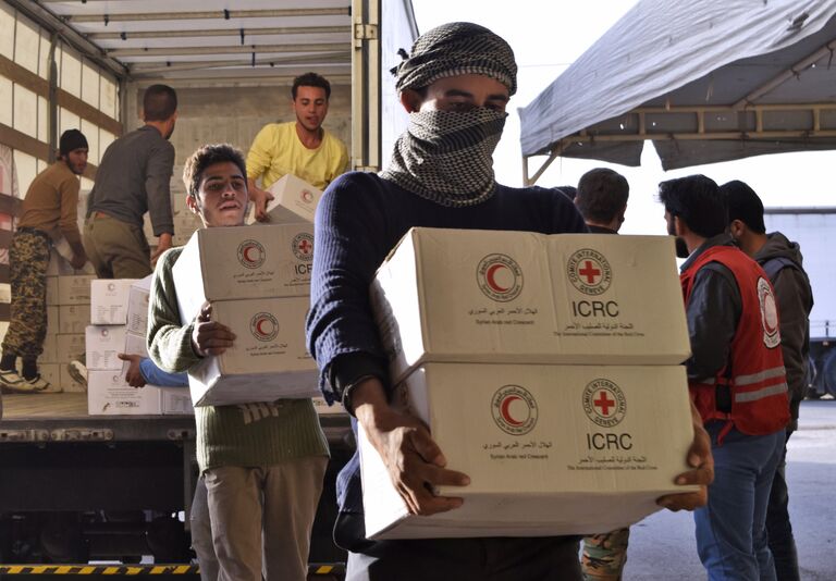 Сирийцы разгружают грузовик с гуманитарной помощью от МККК и Сирийского арабского Красного Полумесяца в Хомсе