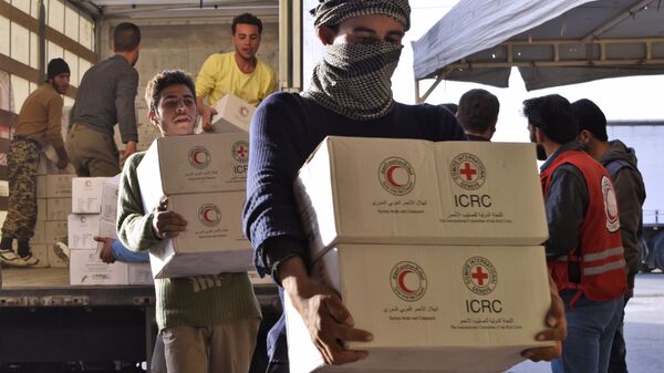Сирийцы разгружают грузовик с гуманитарной помощью от Сирийского арабского Красного Полумесяца