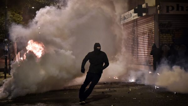 Демонстрант бежит от слезоточивого газа, распыленного греческой полицией в Афинах. 6 декабря 2017 год